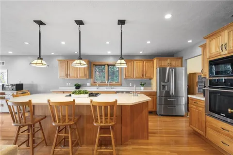 a kitchen with stainless steel appliances kitchen island granite countertop a sink a stove and a wooden floors