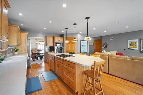 a kitchen with stainless steel appliances kitchen island granite countertop a stove and a wooden floors