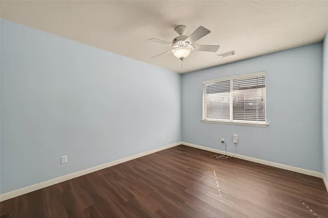 an empty room with wooden floor fireplace and windows