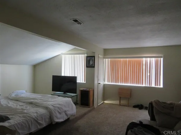a bedroom with bed tv and window