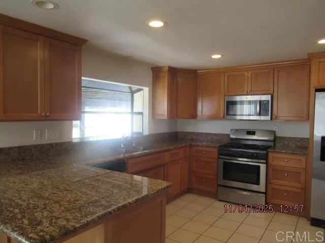 a kitchen with stainless steel appliances granite countertop a stove a sink and a microwave