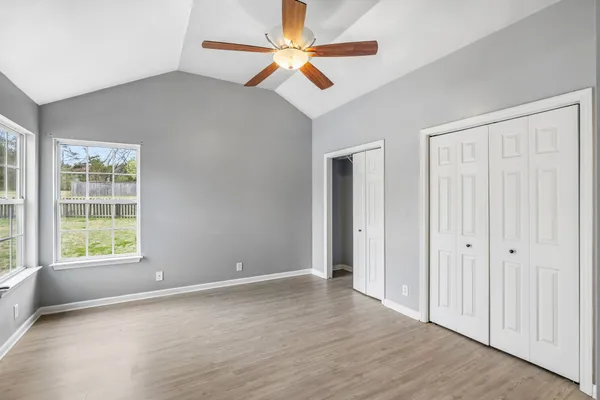 an empty room with chandelier fan and windows