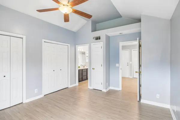 a view of a hallway with wooden floor and a ceiling fan
