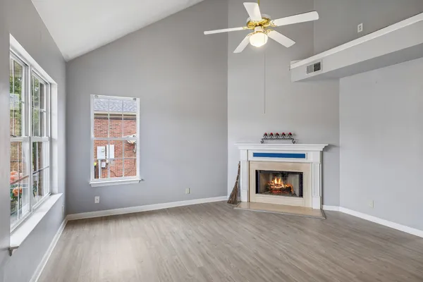 a view of an empty room with wooden floor fireplace and a window