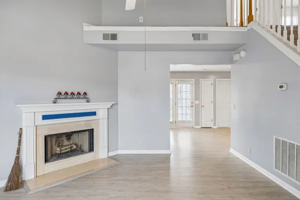 a view of an empty room with wooden floor and a fireplace