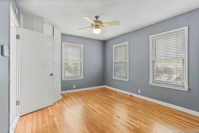 a view of a bedroom with wooden floor and a ceiling fan