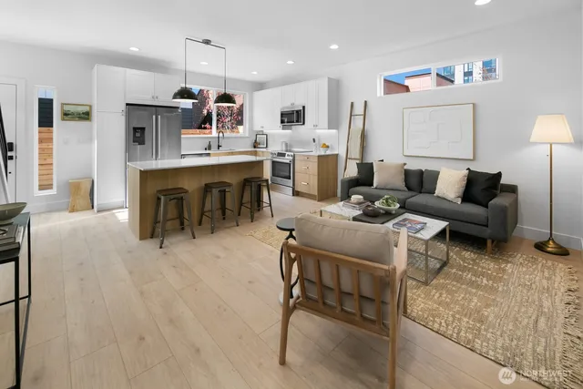 a living room with furniture kitchen view and a wooden floor