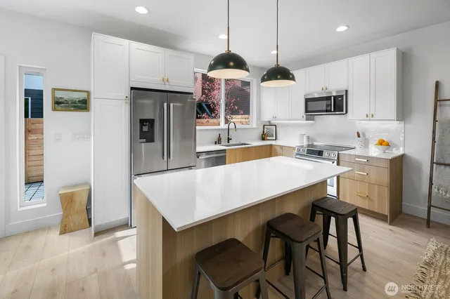 a kitchen with stainless steel appliances a dining table chairs microwave and sink
