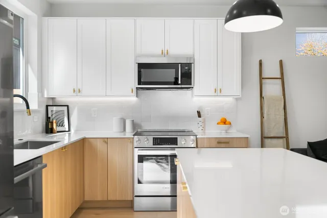 a kitchen with stainless steel appliances a stove a microwave and white cabinets