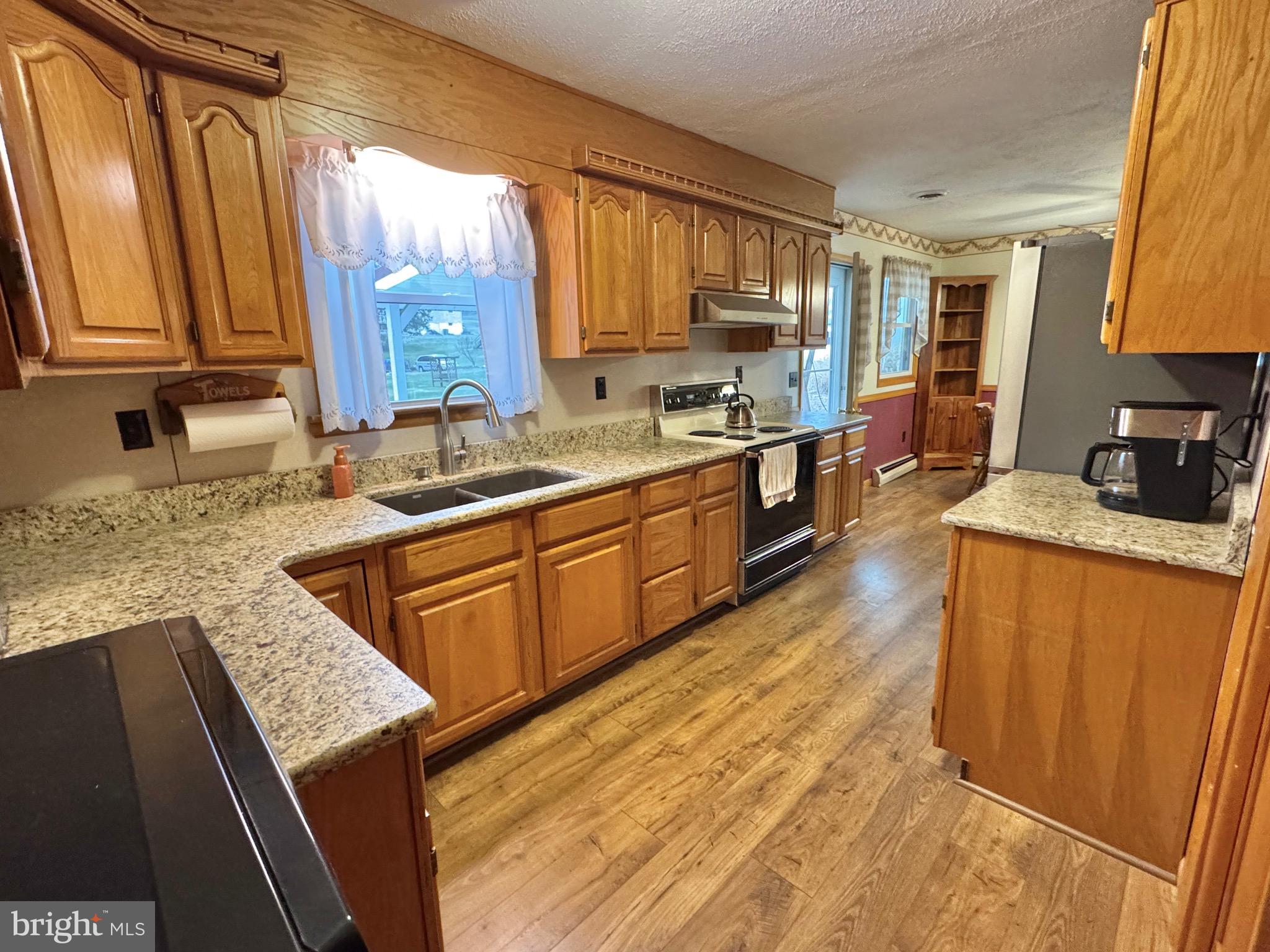 115 Upper Gyp Road Bellefonte, PA 16823 - Photo 8 of 27 a kitchen with stainless steel appliances granite countertop wooden cabinets a sink dishwasher a stove and a refrigerator with wooden floor