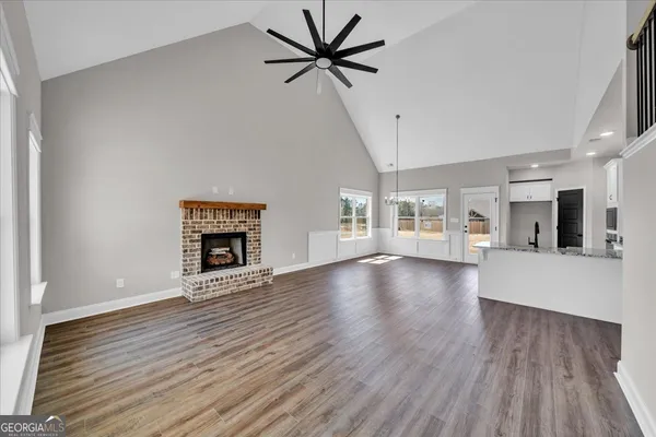 a view of a livingroom with a fireplace a ceiling fan and wooden floor