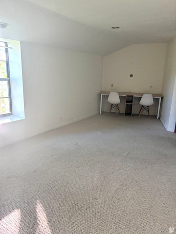 1903 Ridgehollow Drive Bountiful, UT 84010 - Photo 13 of 24 Carpeted room featuring a built-in wood-finish desk with white legs and a central storage unit, a sloped ceiling portion, and a recessed ceiling light