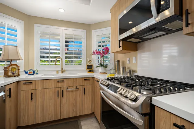 a kitchen with stainless steel appliances a sink a window and cabinets