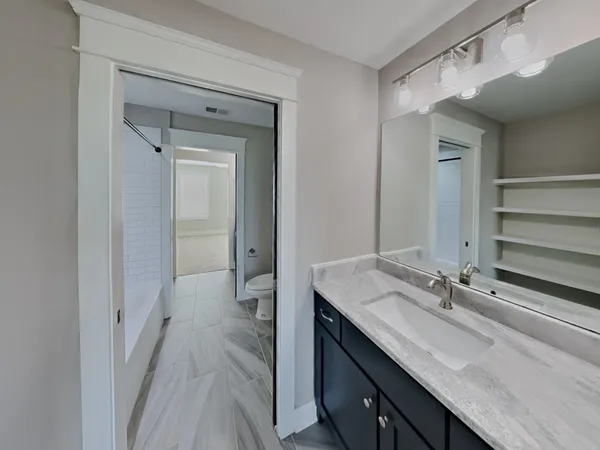 a en suite bathroom with a granite countertop sink and a mirror