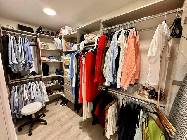a view of walk in closet with clothes and shoes