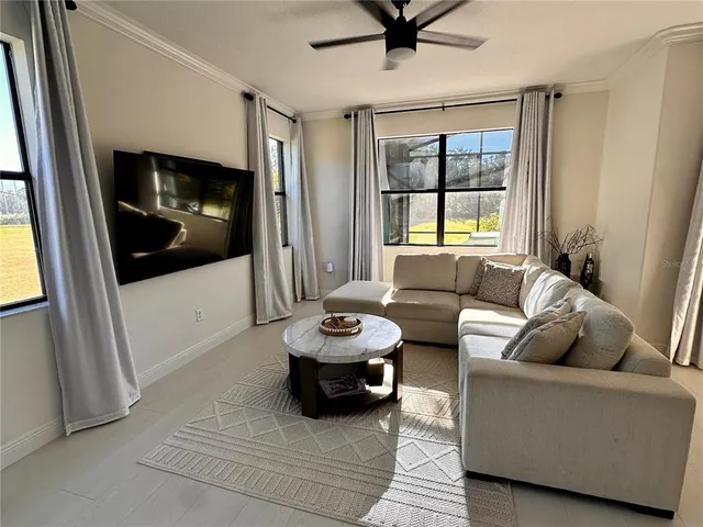 a living room with furniture a flat screen tv and a window