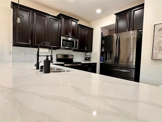 a kitchen with granite countertop a refrigerator and a stove top oven