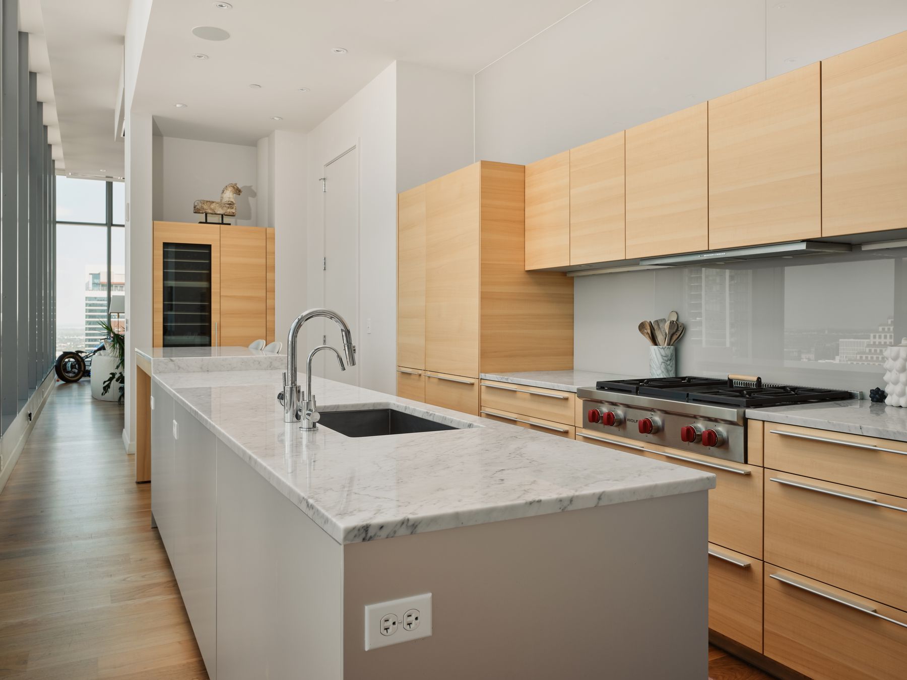 210 Lavaca Street, Unit 3504 Austin, TX 78701 - Photo 17 of 40 Kitchen featuring light brown cabinetry, a kitchen island with sink, modern cabinets, wood finished floors, and expansive windows