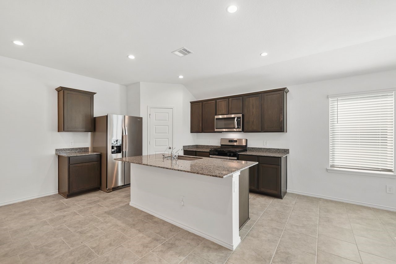 7502 Fierce Friesian Lane Rosharon, TX 77583 - Photo 7 of 21 a kitchen with stainless steel appliances granite countertop a stove top oven a sink dishwasher a refrigerator and a refrigerator with wooden floor