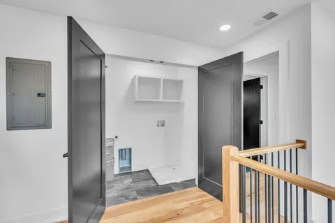 a view of a hallway with wooden floor and a bathroom
