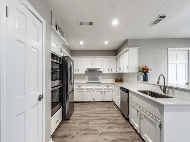 a kitchen with stainless steel appliances kitchen island granite countertop a refrigerator and a sink