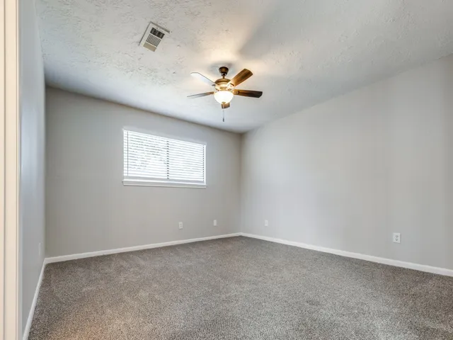 an empty room with a window and a ceiling fan
