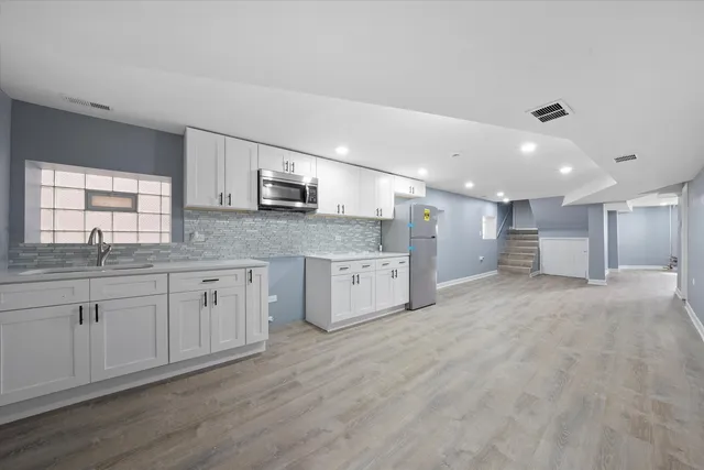 a large kitchen with stainless steel appliances granite countertop a stove a sink and a granite counter tops with white cabinets