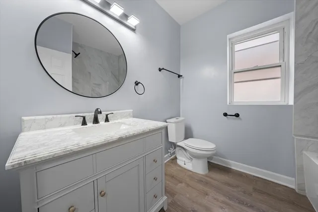 a bathroom with a granite countertop toilet a sink and a mirror