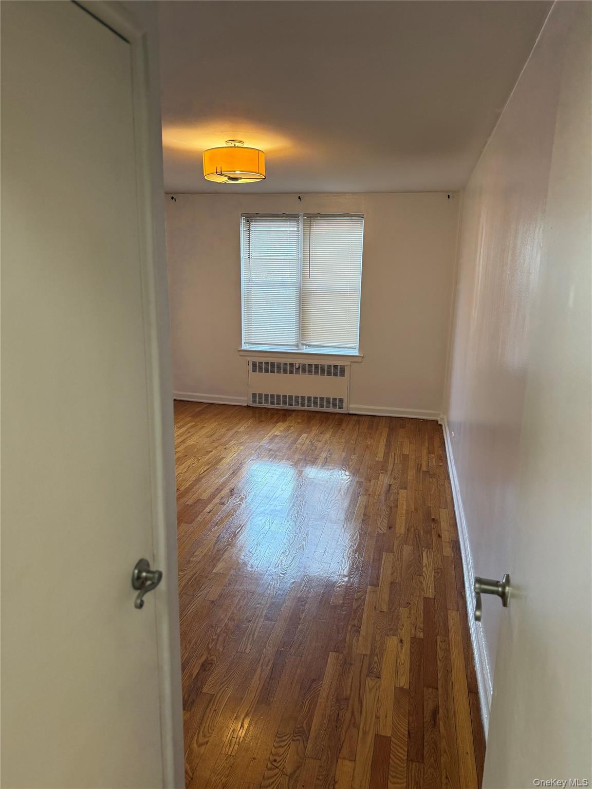 325 East 201st Street, Unit 3J Bronx, NY 10458 - Photo 23 of 33 an empty room with wooden floor and windows