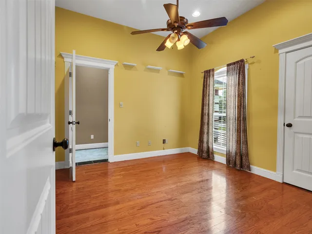 an empty room with wooden floor and a ceiling fan