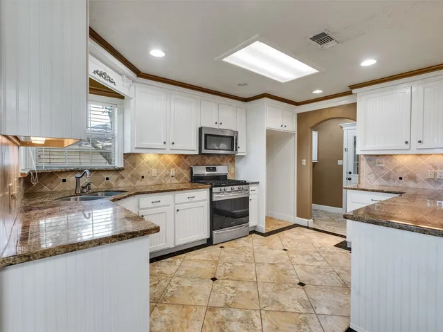 a kitchen with granite countertop a stove a sink and a refrigerator