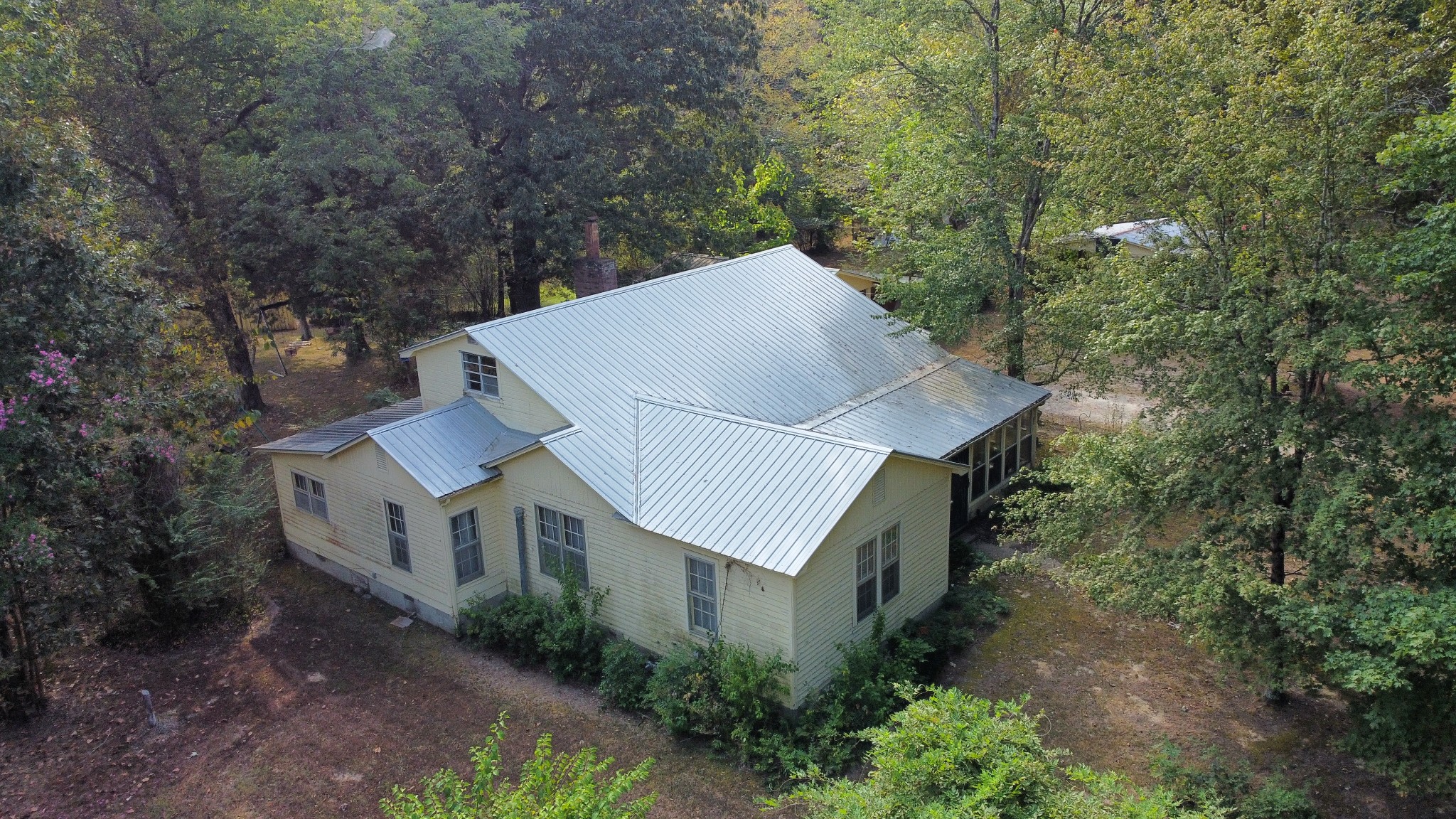 a view of a house with a yard and large trees