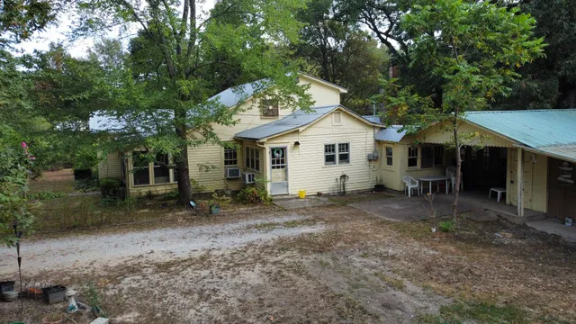 a view of a house with a yard and large tree