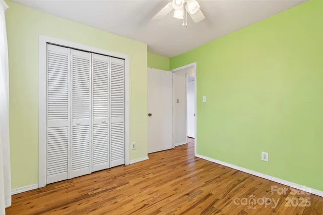 an empty room with wooden floor closet and windows