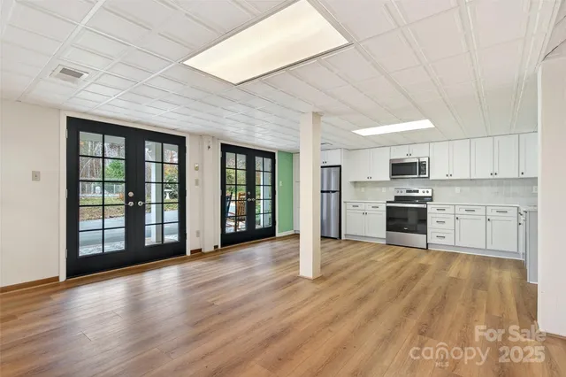 a large kitchen with stainless steel appliances granite countertop a stove top oven a sink dishwasher and white cabinets with wooden floor