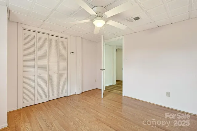 an empty room with wooden floor fan and windows