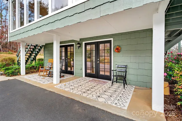 a porch with a table and chair and potted plants in front of door