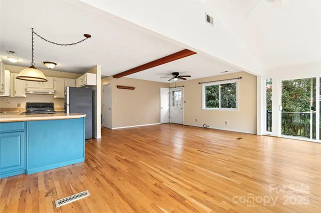 a view of an empty room with window and wooden floor