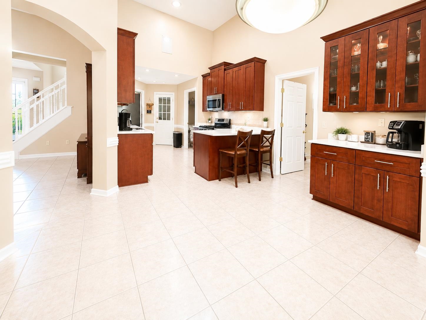 326 South Sanga Road Cordova, TN 38018 - Photo 15 of 32 Spacious kitchen featuring high ceilings, light-toned tile flooring, rich wood cabinetry, white countertops, and an integrated kitchen island with seating