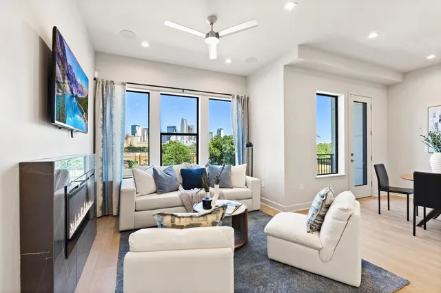 a living room with furniture large window and flat screen tv