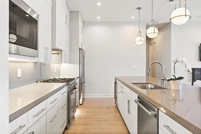 a kitchen with stainless steel appliances granite countertop a sink a stove and a wooden floors