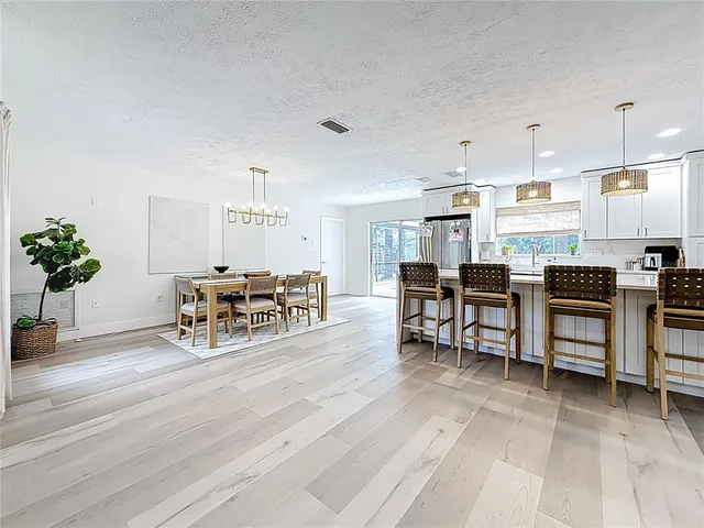 a living room with furniture and kitchen view with potted plants