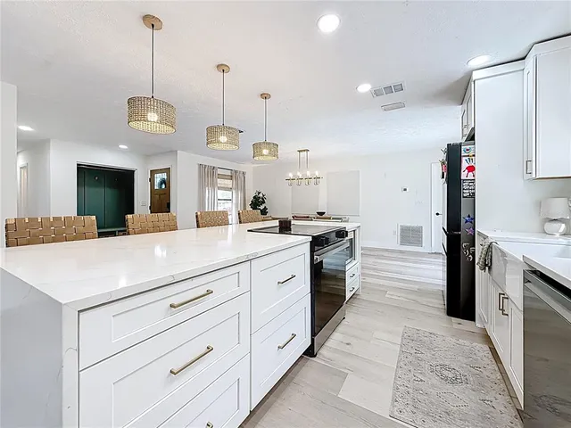 a large kitchen with granite countertop a large stove a sink dishwasher and a refrigerator with wooden floor