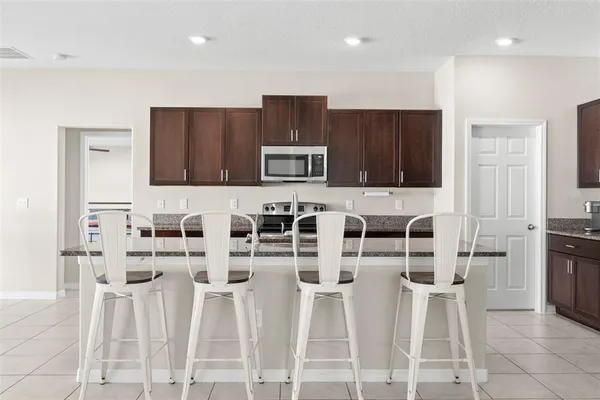 a kitchen with stainless steel appliances granite countertop a stove a sink a microwave a refrigerator and cabinets