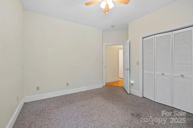 an empty room with a chandelier fan and closet area