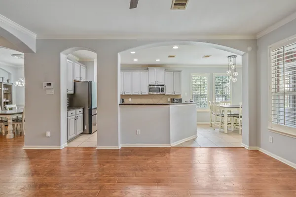a view of a kitchen with kitchen island wooden floors stainless steel appliances and windows