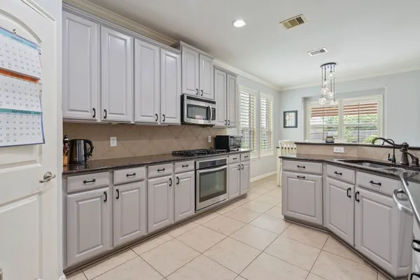 a kitchen with granite countertop white cabinets and stainless steel appliances