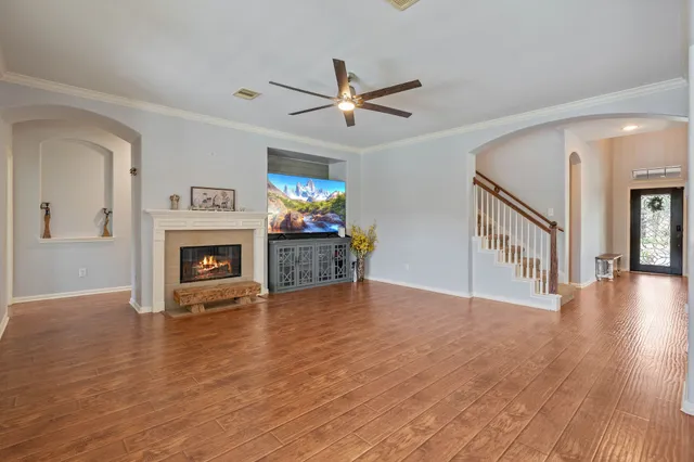 a view of an empty room with wooden floor fireplace and a window