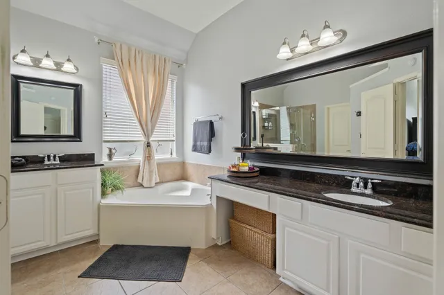 a bathroom with a bathtub a double vanity sink and a mirror