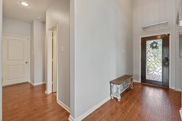 a view of a hallway with wooden floor and a bathroom